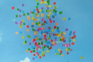Massor med ballonger som svävar iväg mot en blå himmel