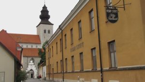 Ett gult hus med texten Visby stift på, med Visby domkyrka i bakgrunden