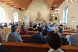 En fylld kyrka med prästen fram vid altaret